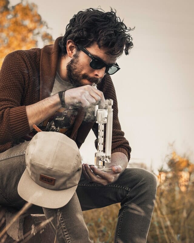 guy smoking a bong in the forest