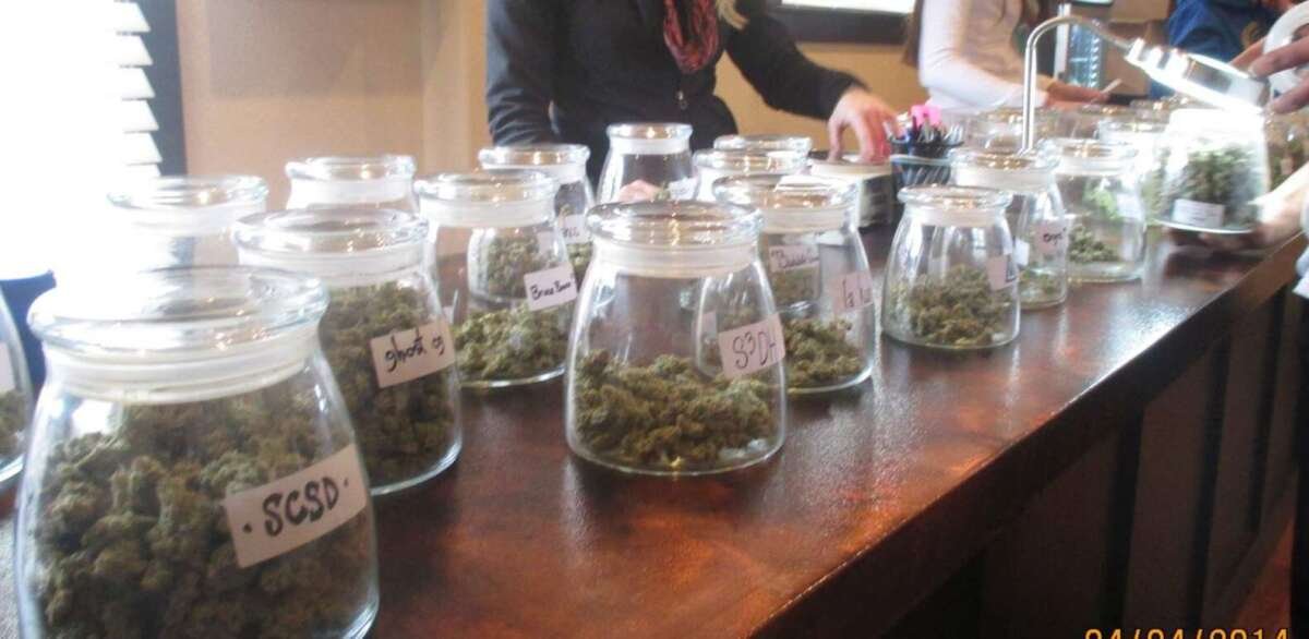 counter of recreational dispensary with many various cannabis strains in jars