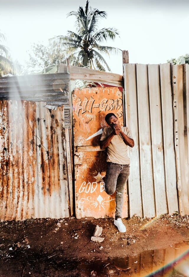 Jamaica man smoking cannabis next to a wall advertising it for sale