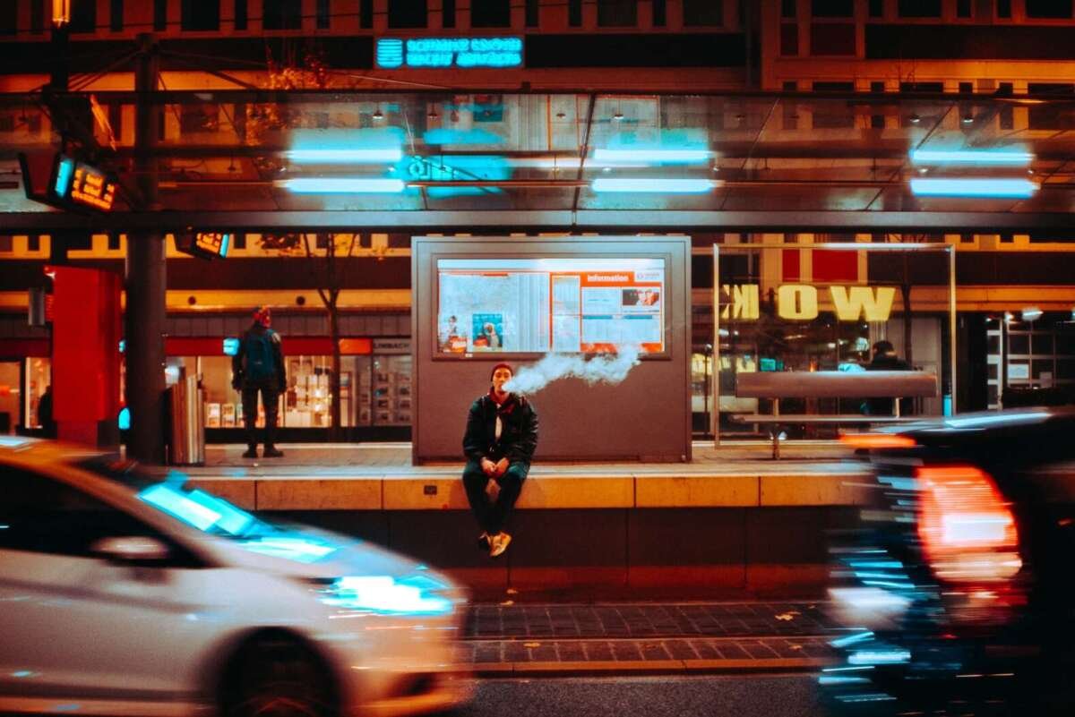 man sitting on train platform vaping