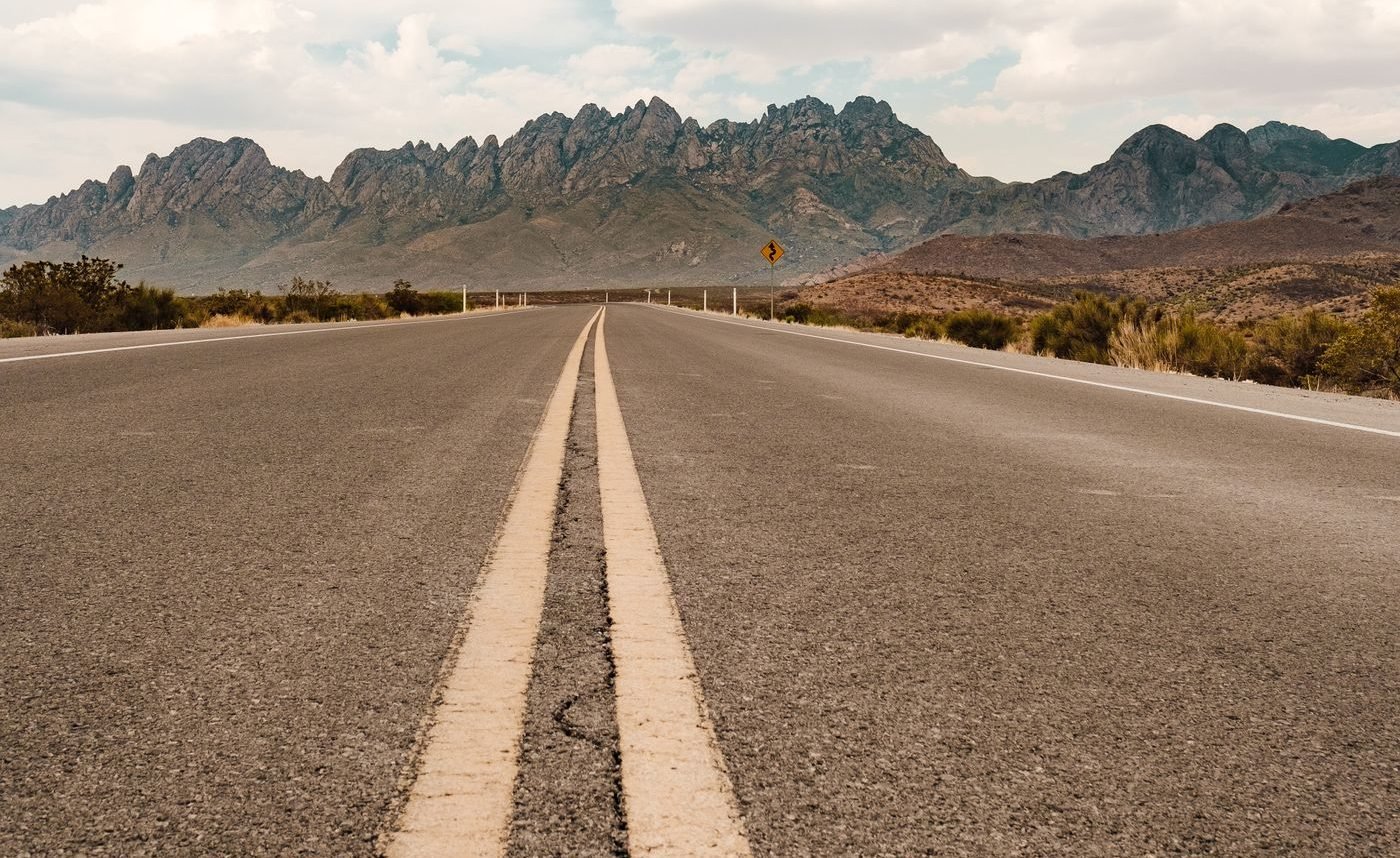 An empty paved road leading toward the Organ Mountains near Las Cruces